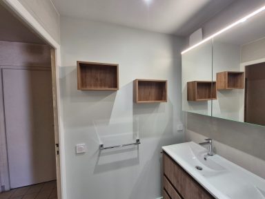 Salle de bains moderne avec un meuble vasque, miroir et étagères murales en bois.