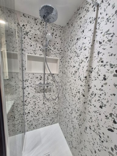 Douche moderne avec paroi en verre et carreaux décoratifs noirs et blancs.